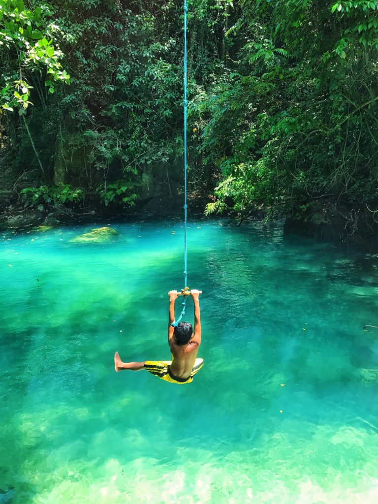 photo of boy swinging over body of water 2413238